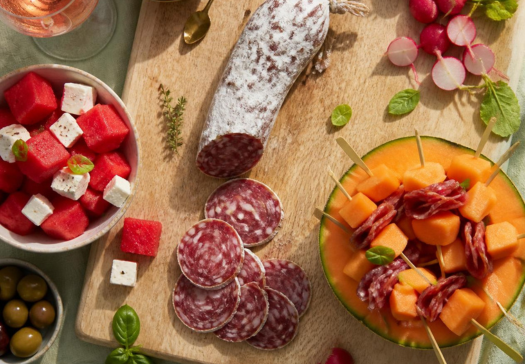 Table d'apéro d'été avec saucisson, brochettes melon et crudités fraîches