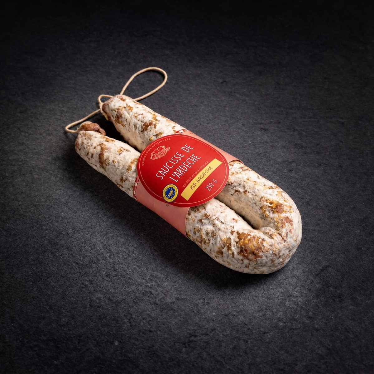 Gebogene Trockenwurst aus der Ardèche g.g.A., 230 g, in Hufeisenform, mit Etikett auf anthrazitgrauem Hintergrund