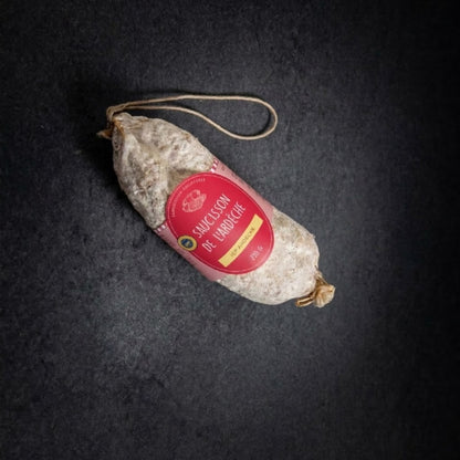 Ganze Trockenwurst aus der Ardèche g.g.A. mit Etikett und Aufhängeschnur, von oben auf dunklem Hintergrund