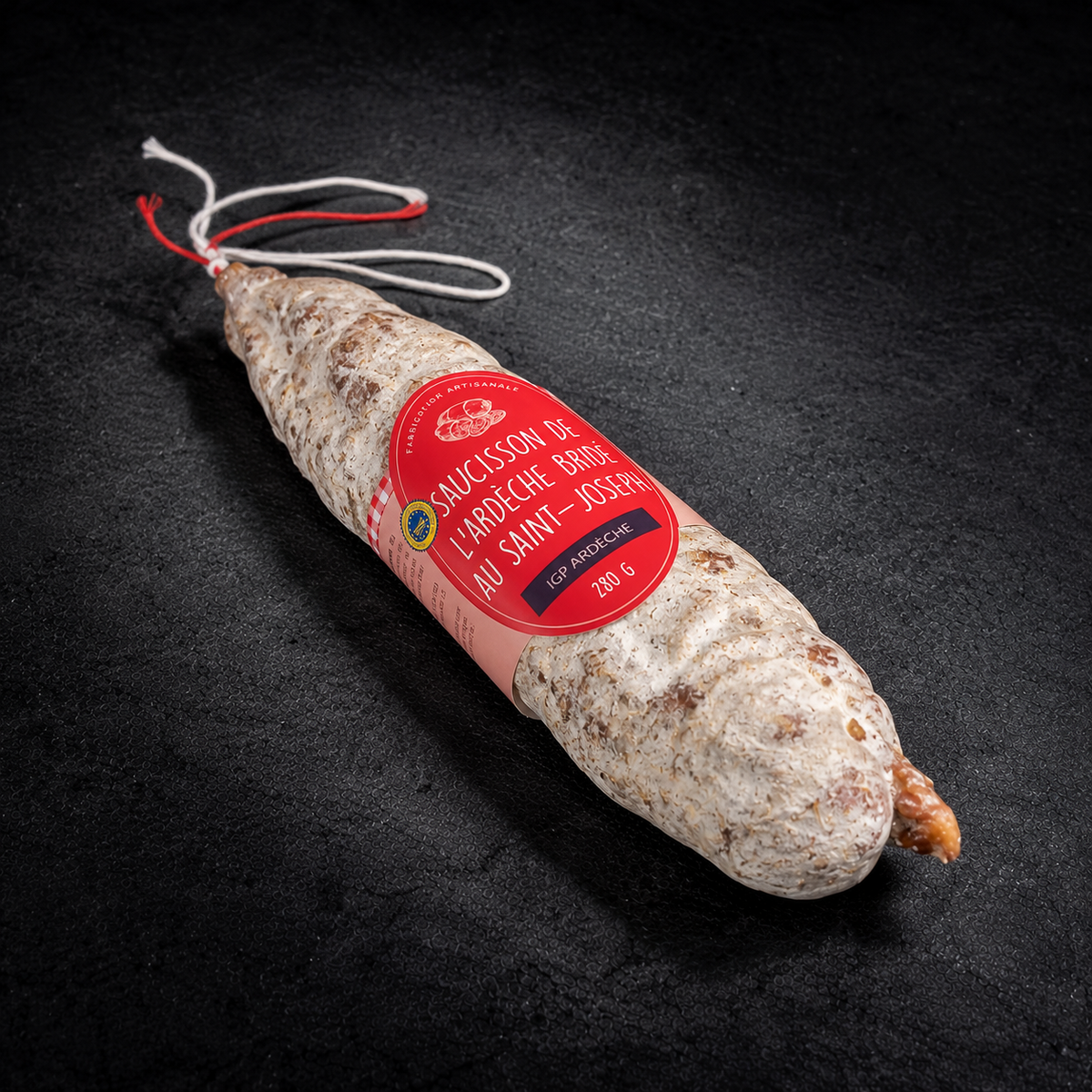 Hand-tied Saint-Joseph red wine saucisson, Ardèche PGI, 280 g, with its label on a black slate background