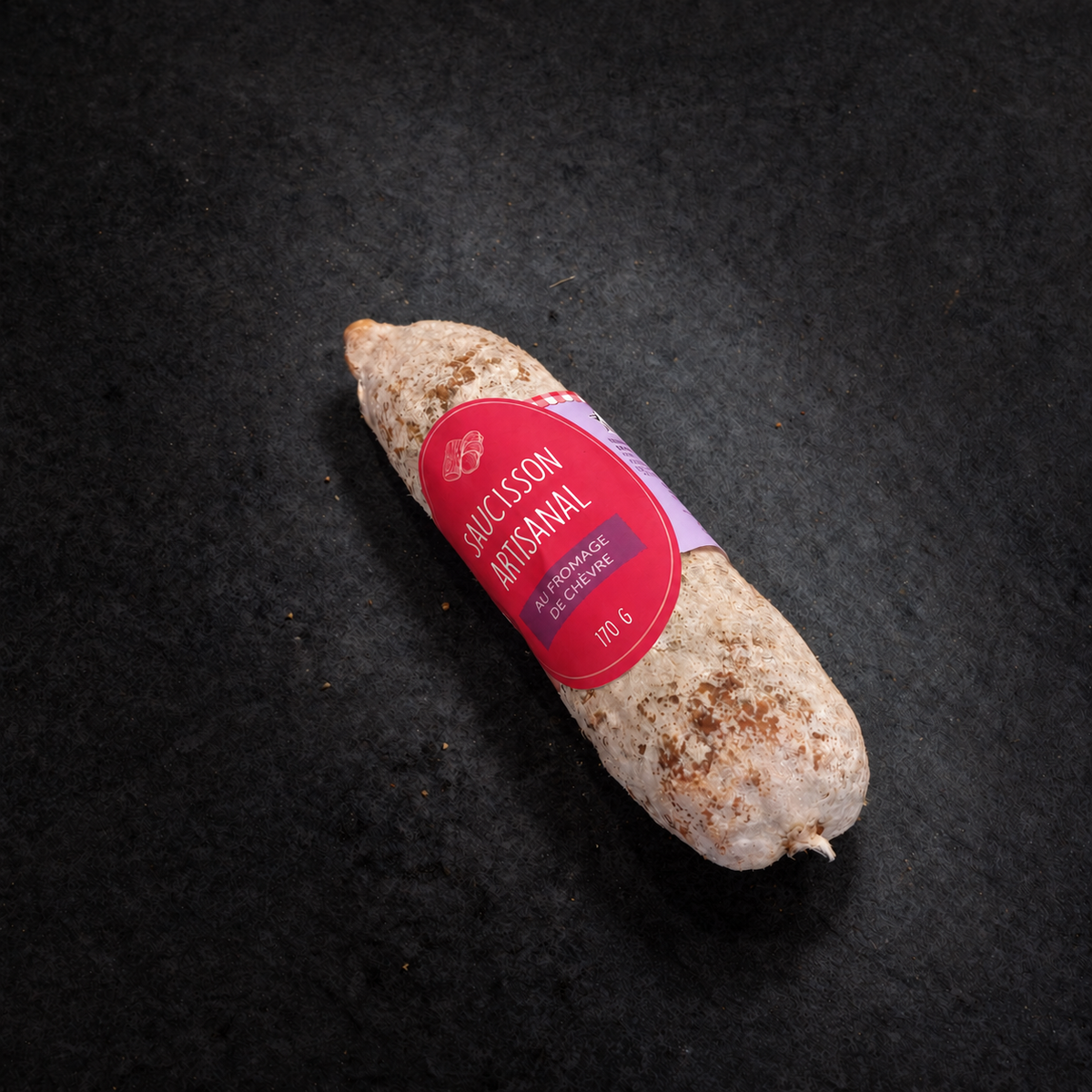 Artisan dry-cured saucisson with goat's cheese worked into the sausage, 170 g, with its label on a black slate background