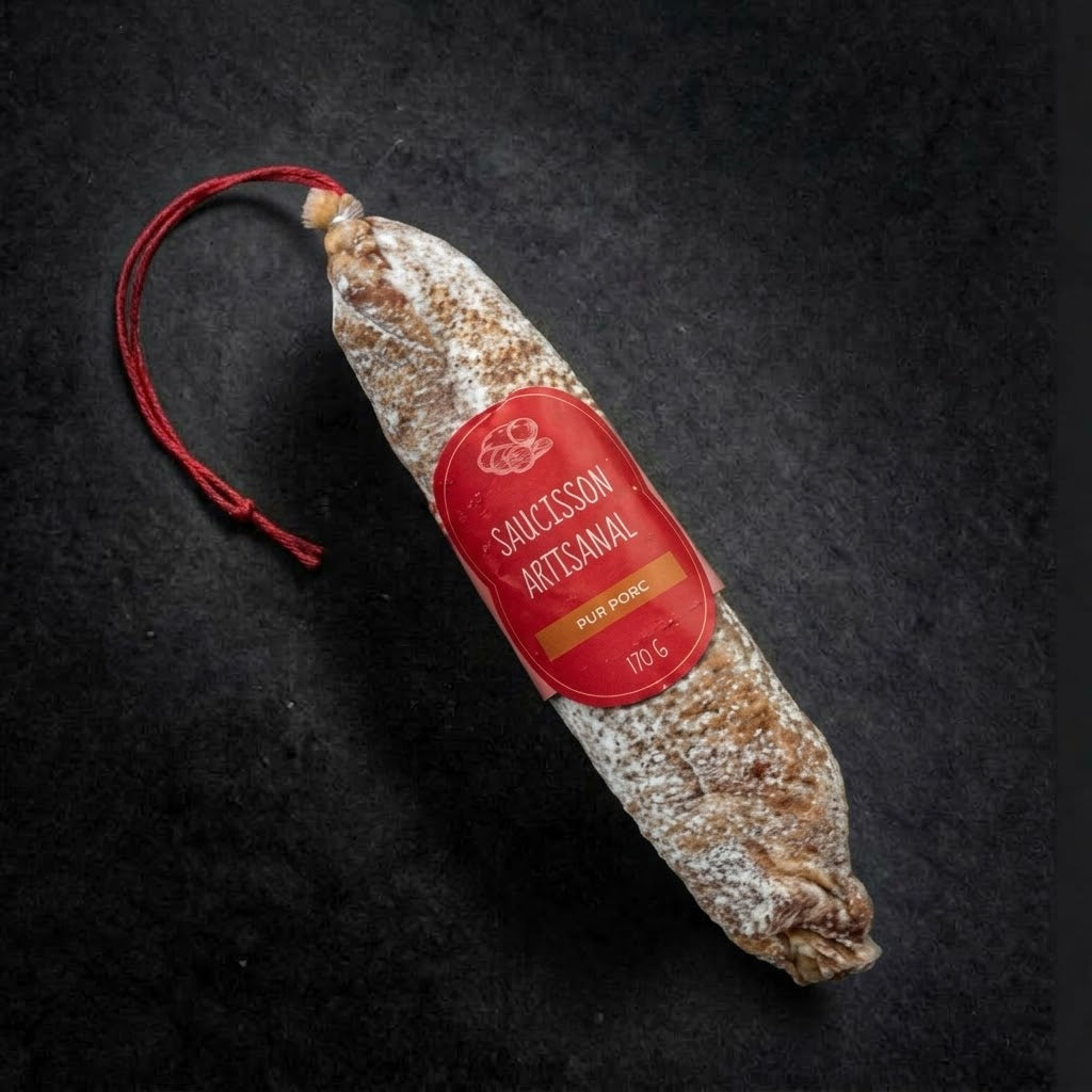 Artisan pure pork dry-cured saucisson, 170 g, with its red hanging string and label on a black slate background